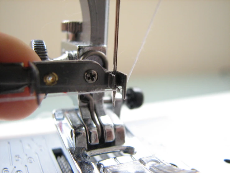 someone is holding the needle and threading it on a sewing machine
