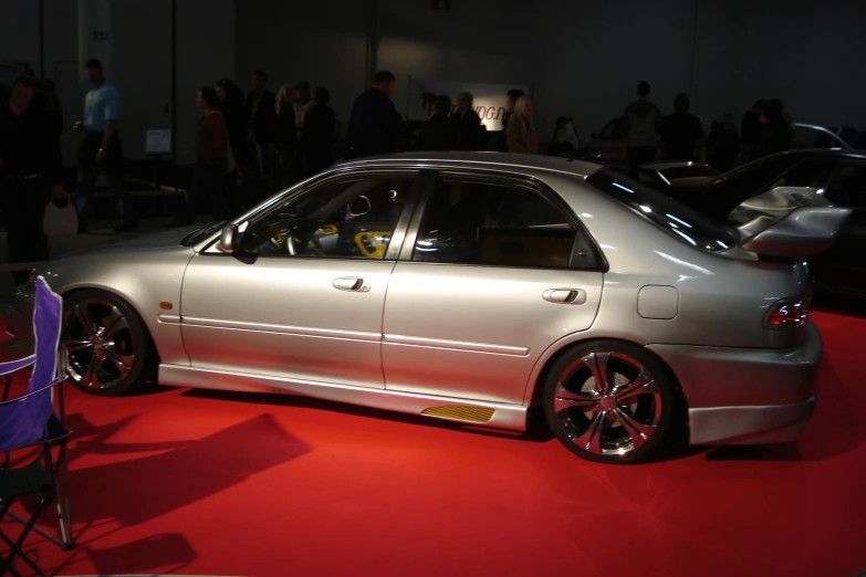 a very shiny silver car on a red carpet in a building