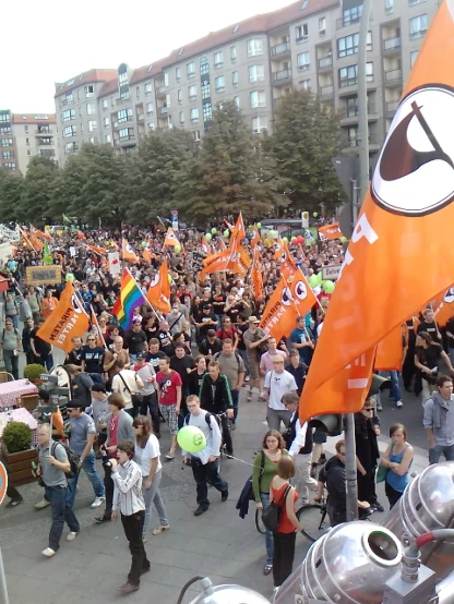 an outdoor gathering of people holding orange flags
