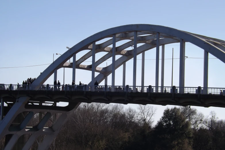 some people are walking across a bridge and a blue sky