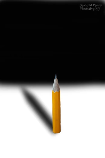 a pencil shadow on a white table next to black background