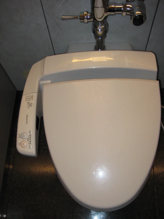 a toilet bowl is white with an electronic device