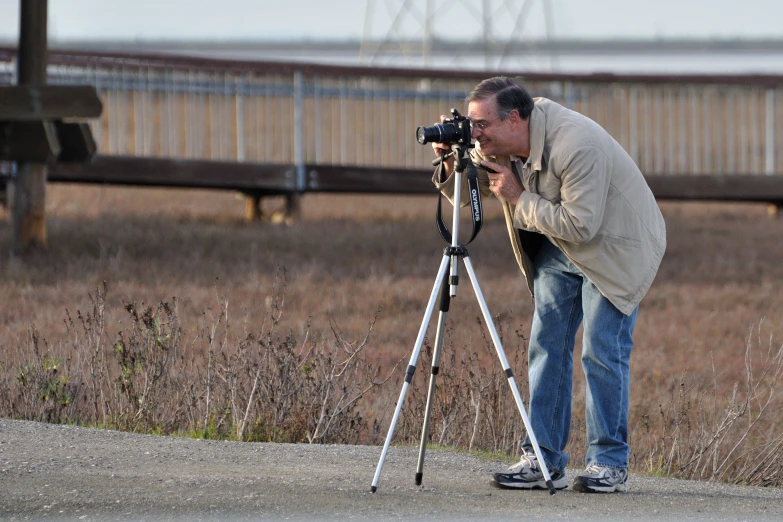 a man looking at soing and using a tripod to take it