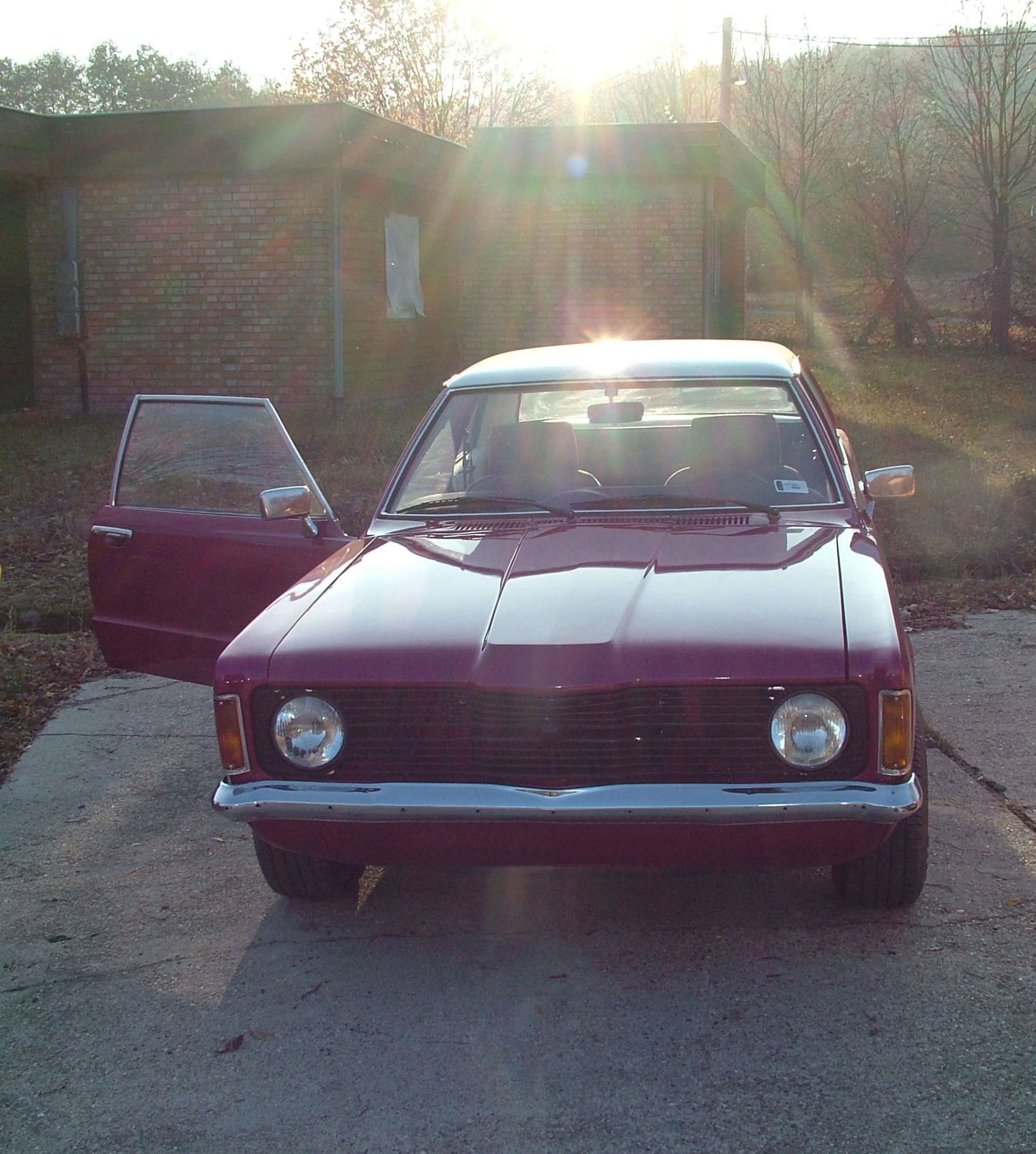 a car with a sun glaring from behind it