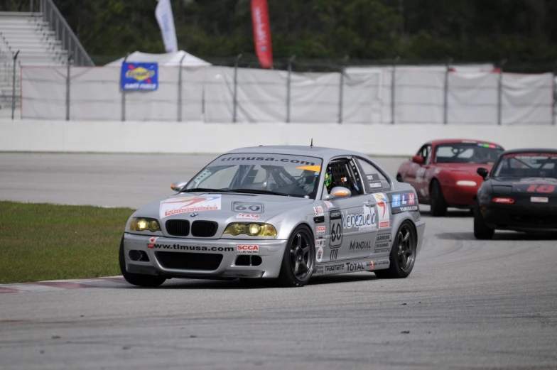 a silver car driving down a race track