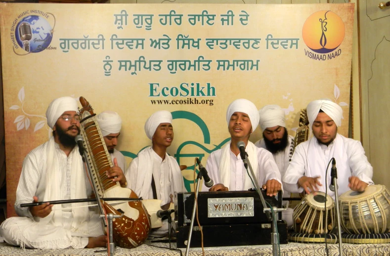 several men dressed in white and sitting behind two drums