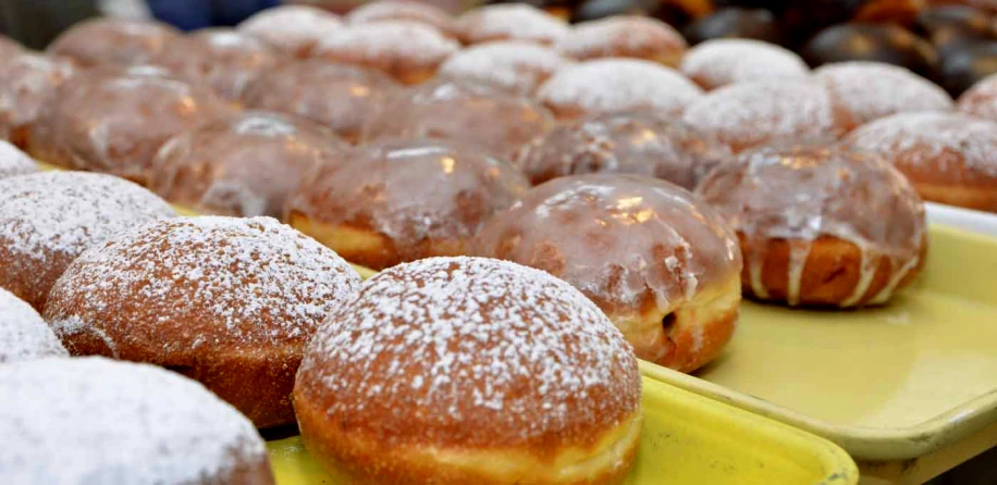 close up of donuts on yellow trays with powdered sugar