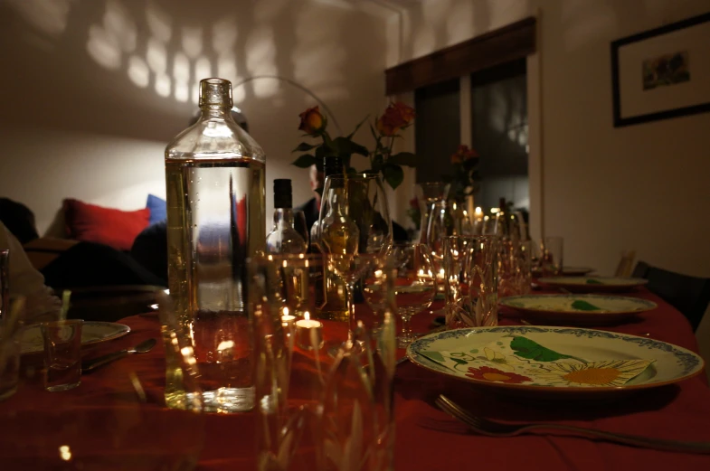 a table with glasses and plates on it, and a bottle next to the plate