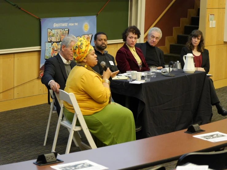 an audience sits in front of a black table