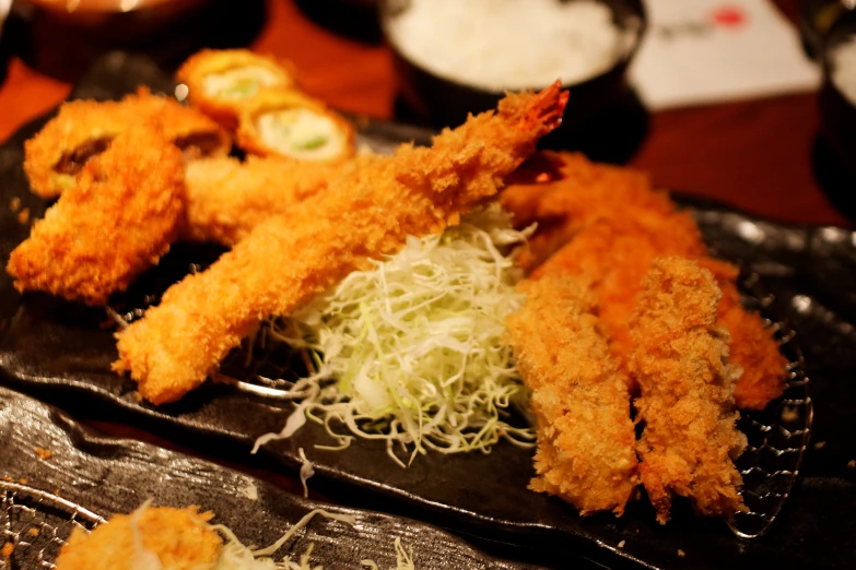 fried food items with sprouts served on black paper