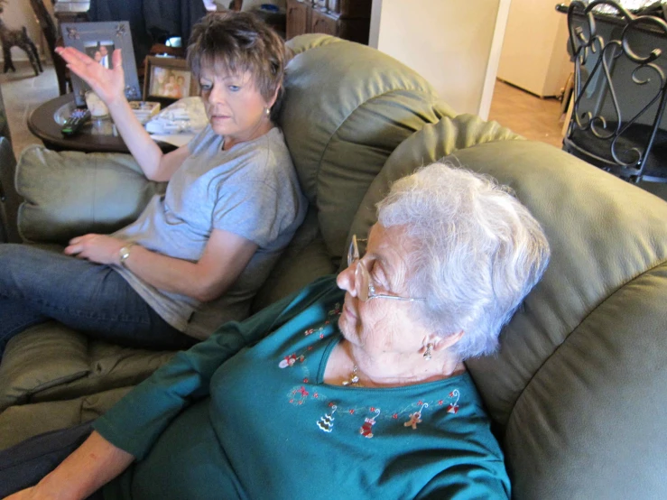 two older women on couches one is waving