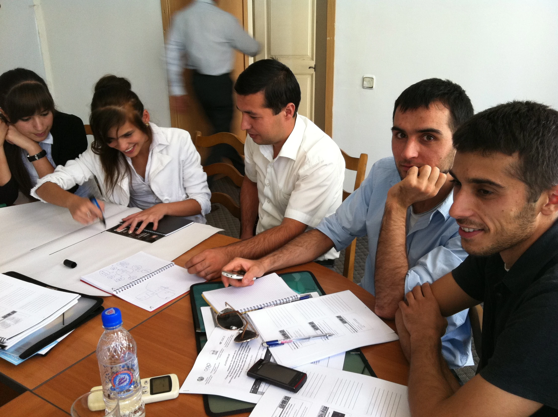 four people sitting around a table in front of a laptop computer