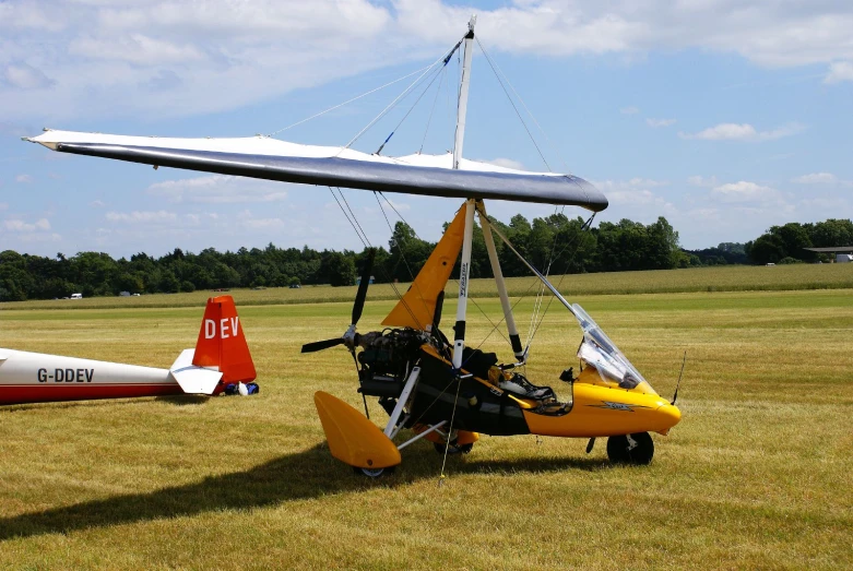 a single engine airplane parked on grass next to an airplane that has been mounted on it