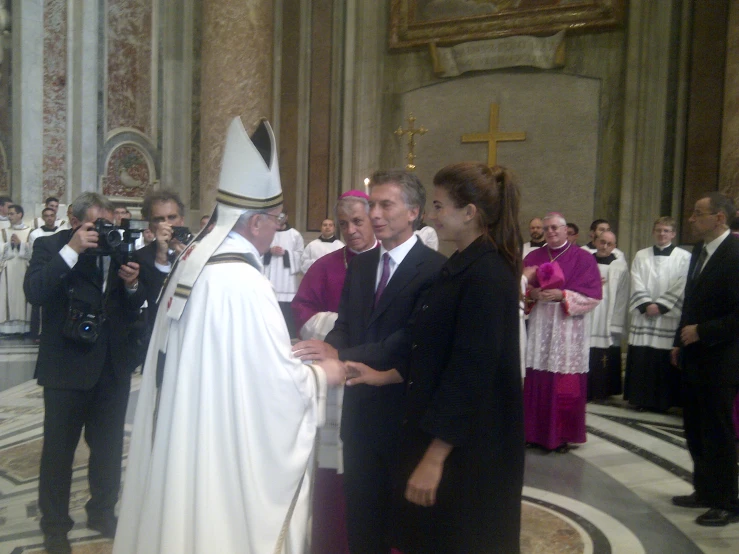 a priest shakes hands with two men on a city street