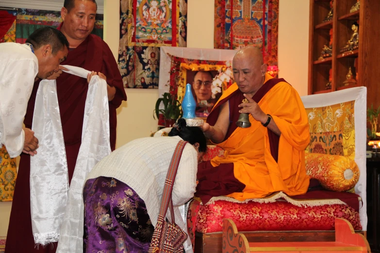 two men standing near another sitting down with priest