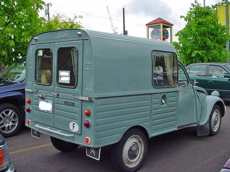 an old, green vehicle parked in a parking lot