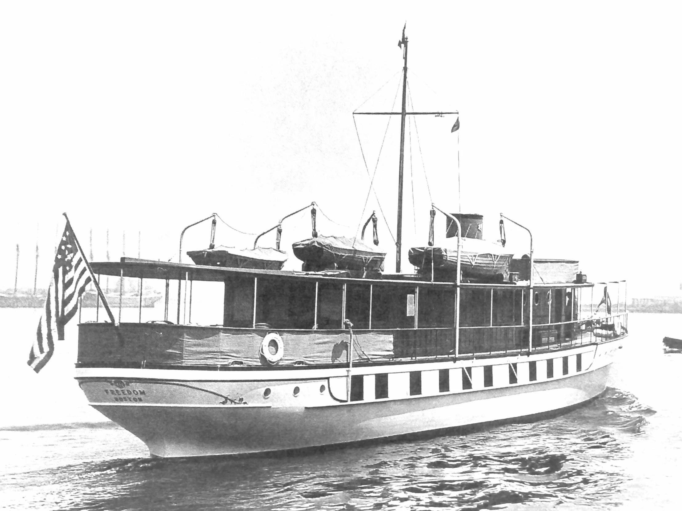 large white boat traveling down the water in front of a flag