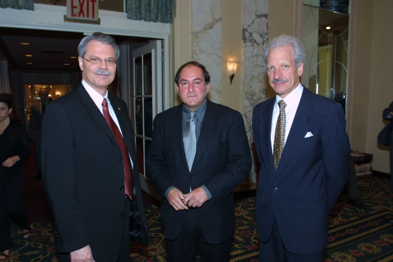 three men standing beside each other and a doorway