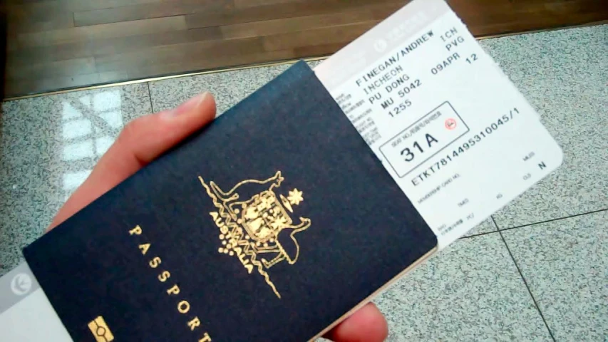 a person is holding their passport over some boarding papers