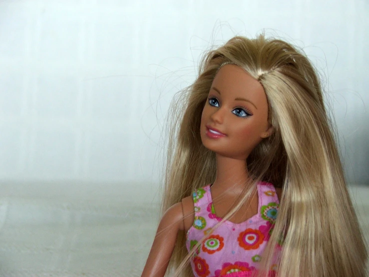 a doll with long blonde hair on a bed