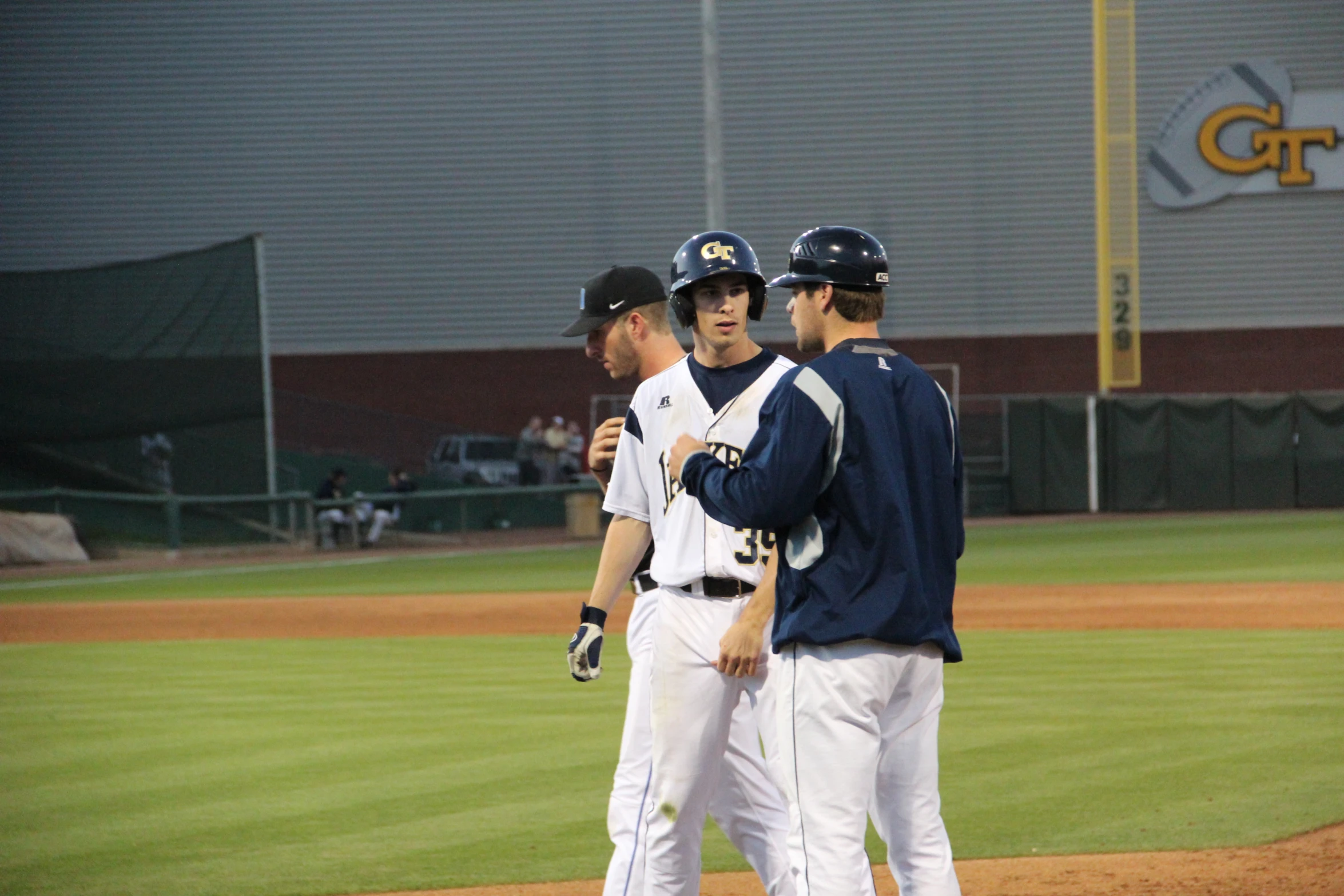 a group of men standing on a baseball field talking to each other