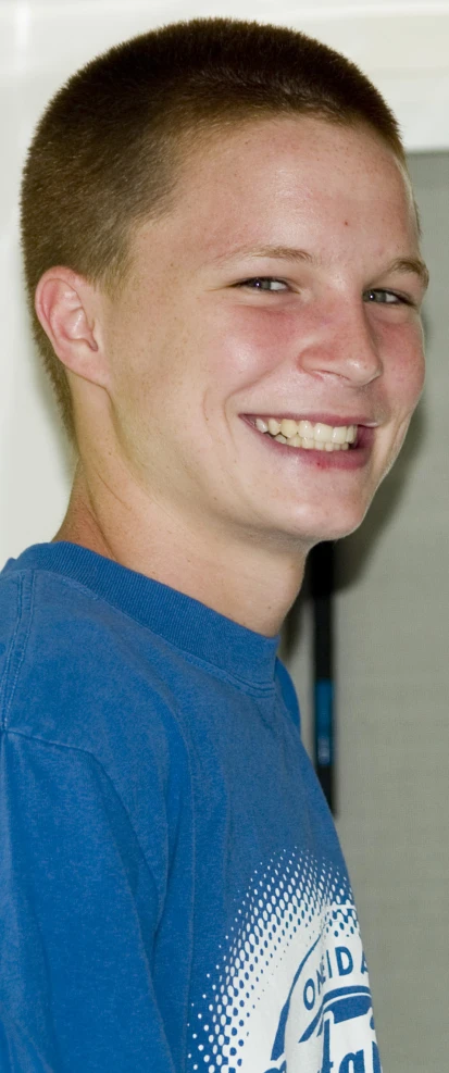 a smiling boy wearing a blue shirt in his home