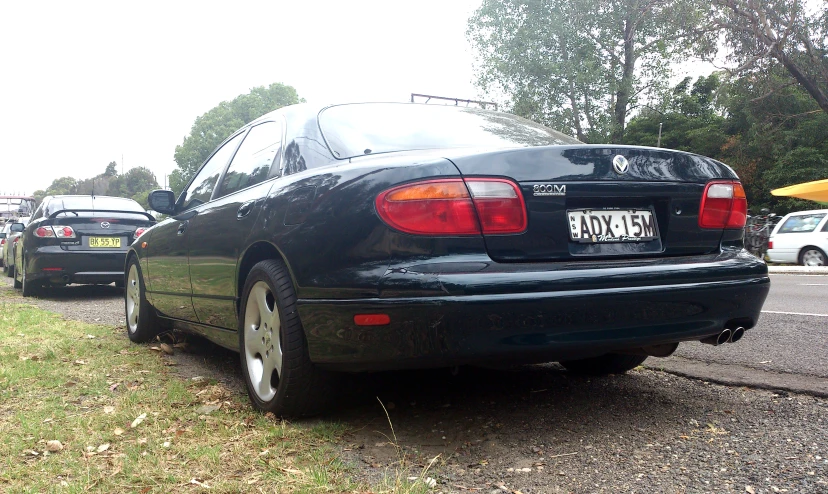 a black bmw parked on the street in front of other cars