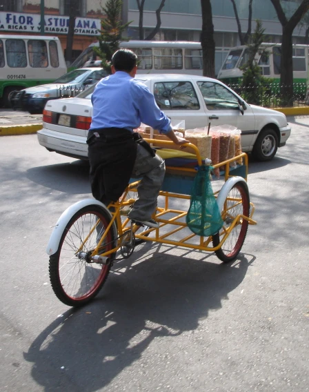 a man riding his bike carrying items in a cart