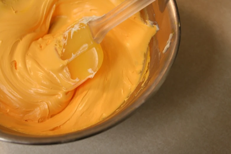 a bowl with yellow er and a plastic spatula