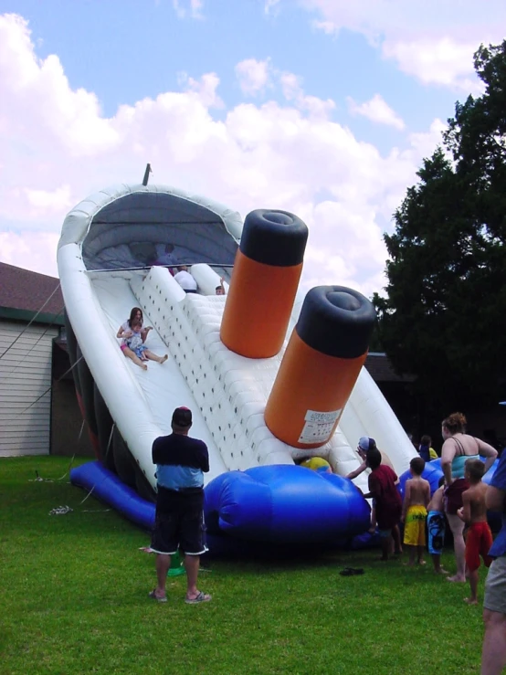 a group of people are standing near an inflatable water slide