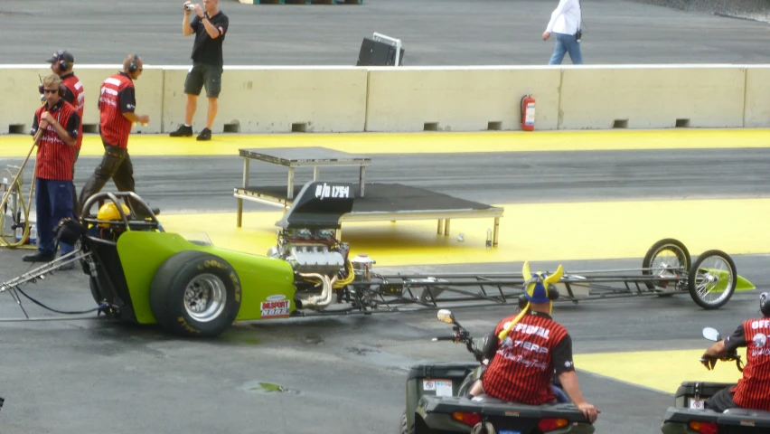 a number of people working on a green car