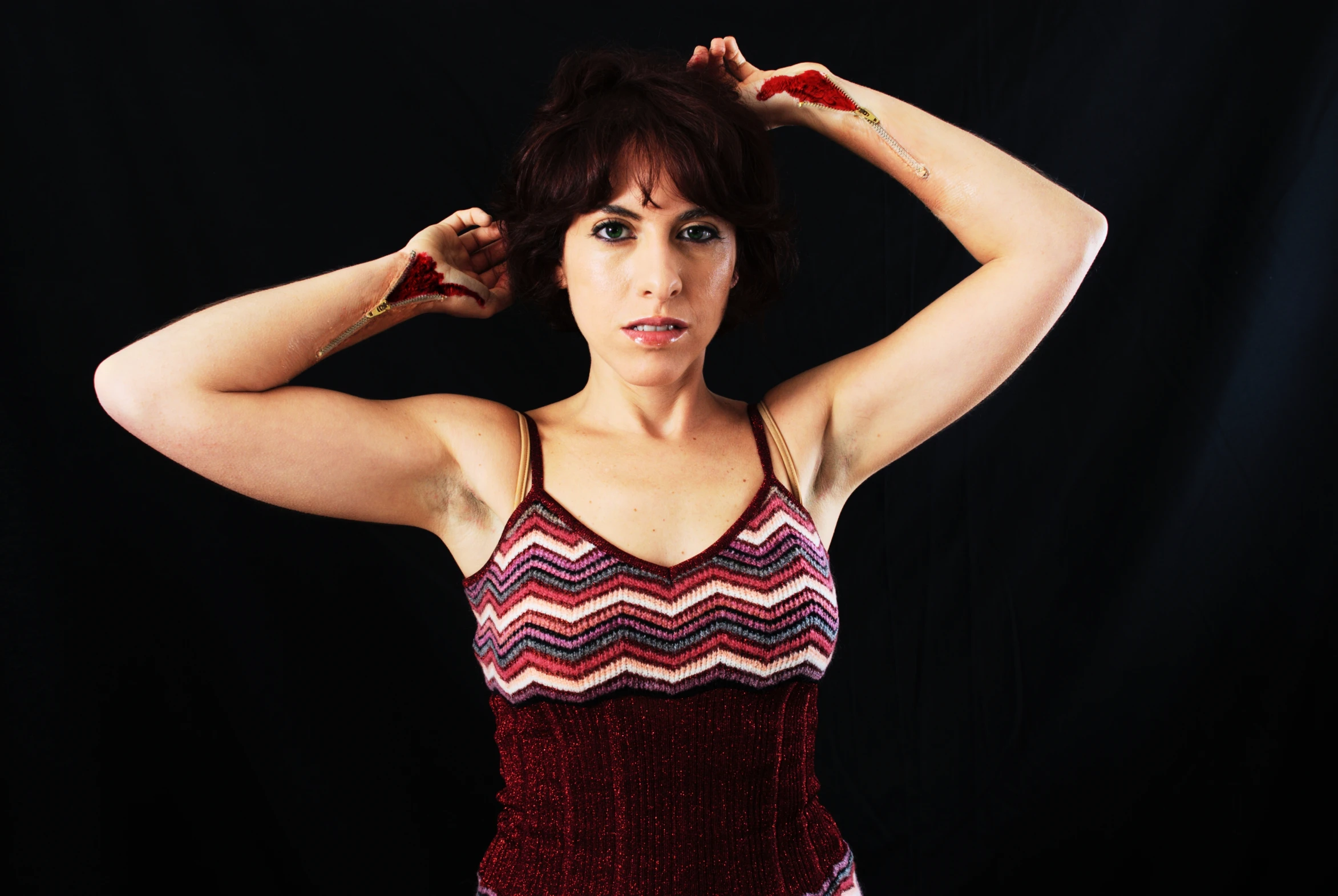 a beautiful woman standing next to a wall with her hands on her head