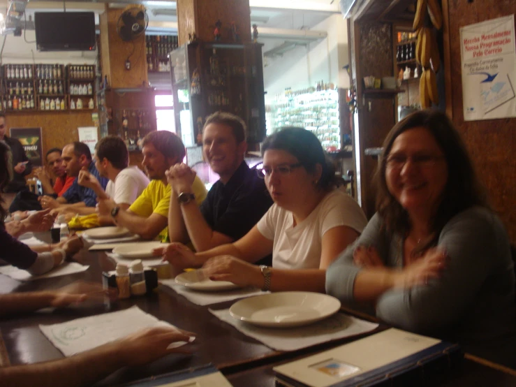 a bunch of people sitting at a table in a restaurant with plates and wine glasses