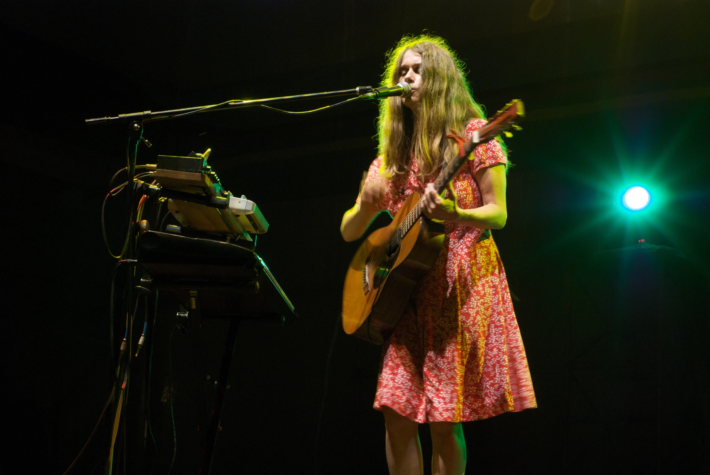 a woman on stage playing guitar next to a keyboard