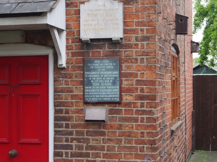 the front of a building with brick walls and a red door