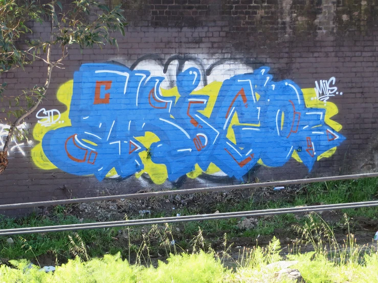 some blue, yellow and white graffiti on a brick wall