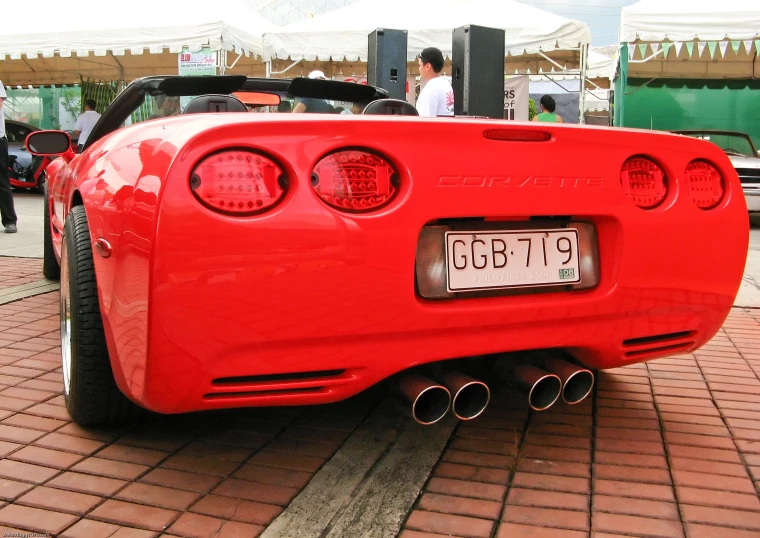 the rear end of a red sports car parked on brick