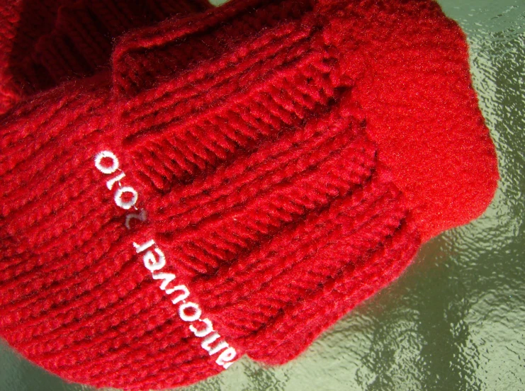 red knit hat with white logo on it and name written in large letters