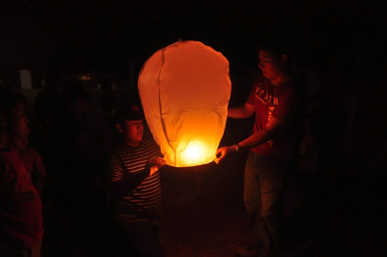 people are looking at a floating lantern in the dark