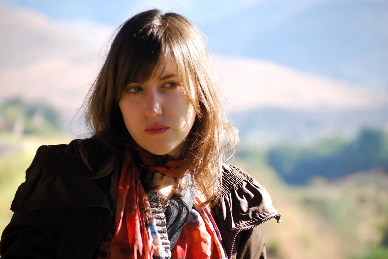 a young woman standing outside with the sun on her shoulder