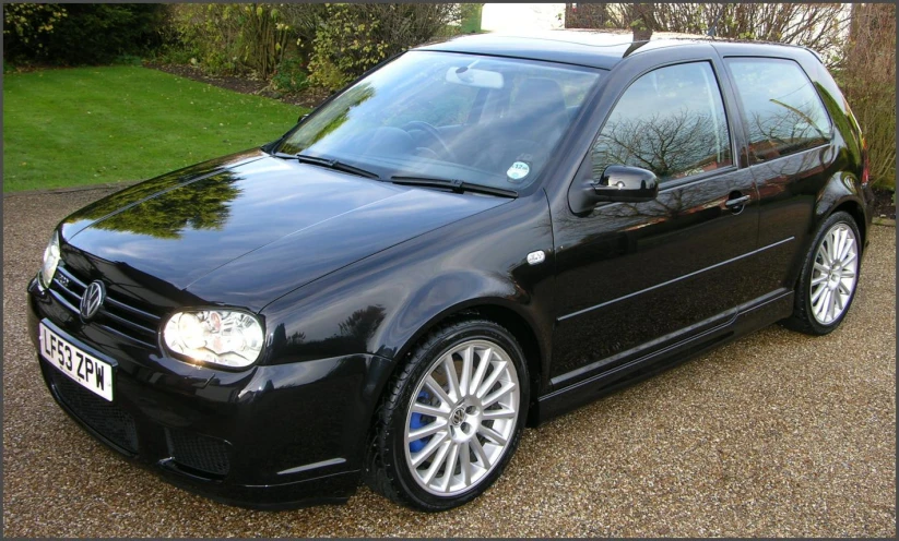 a dark colored car is parked in front of a tree