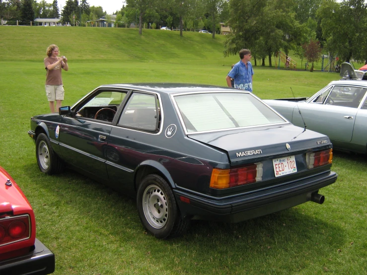 people stand around parked vehicles on a green field