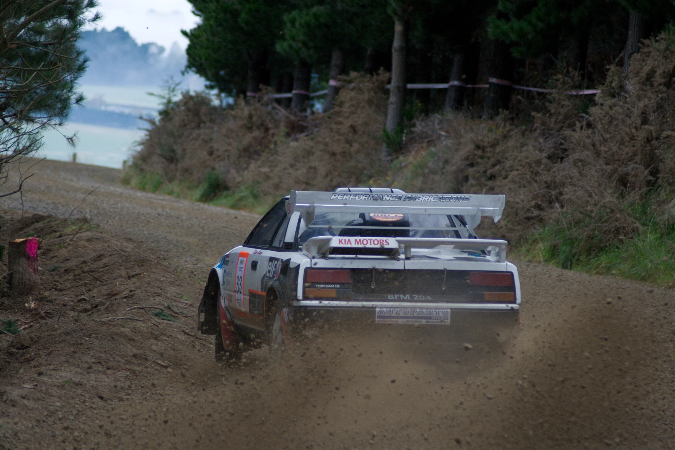 a dirt covered road with a race car racing through the mud