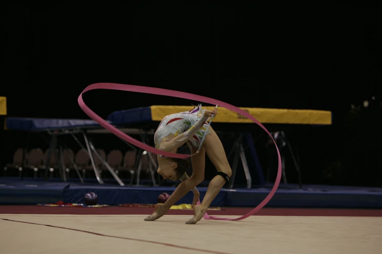 a female figure holding a hula hoop and performing a trick