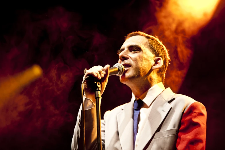 a man singing into a microphone with smoke coming from the top