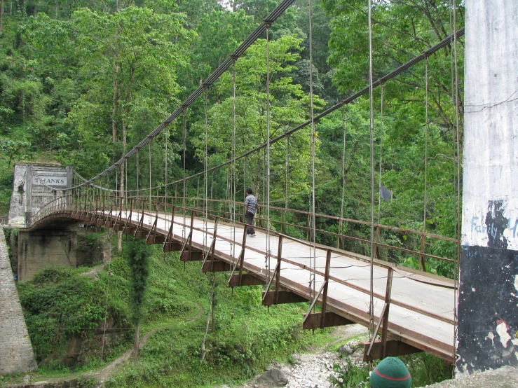 a man is walking across a wooden bridge