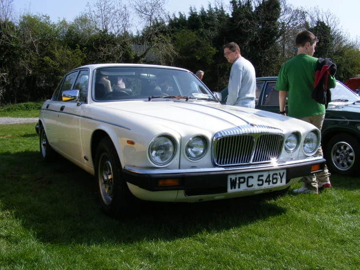 a man looking at a white jaguar car on display