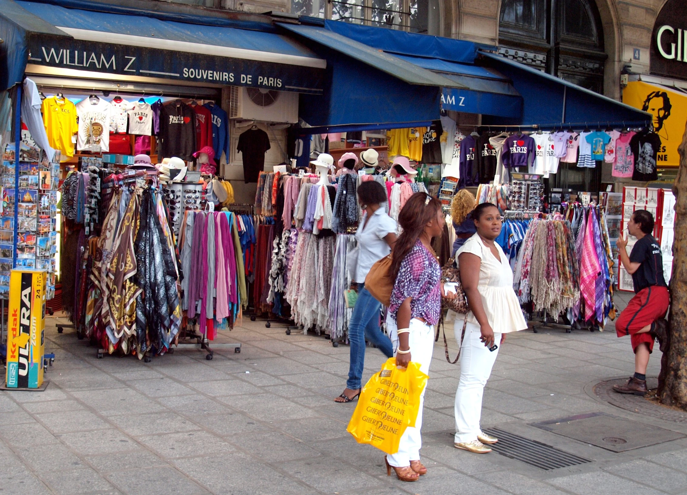 two women on the sidewalk standing next to clothes