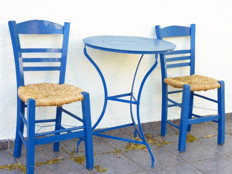 two blue chairs sitting side by side with a table and chair