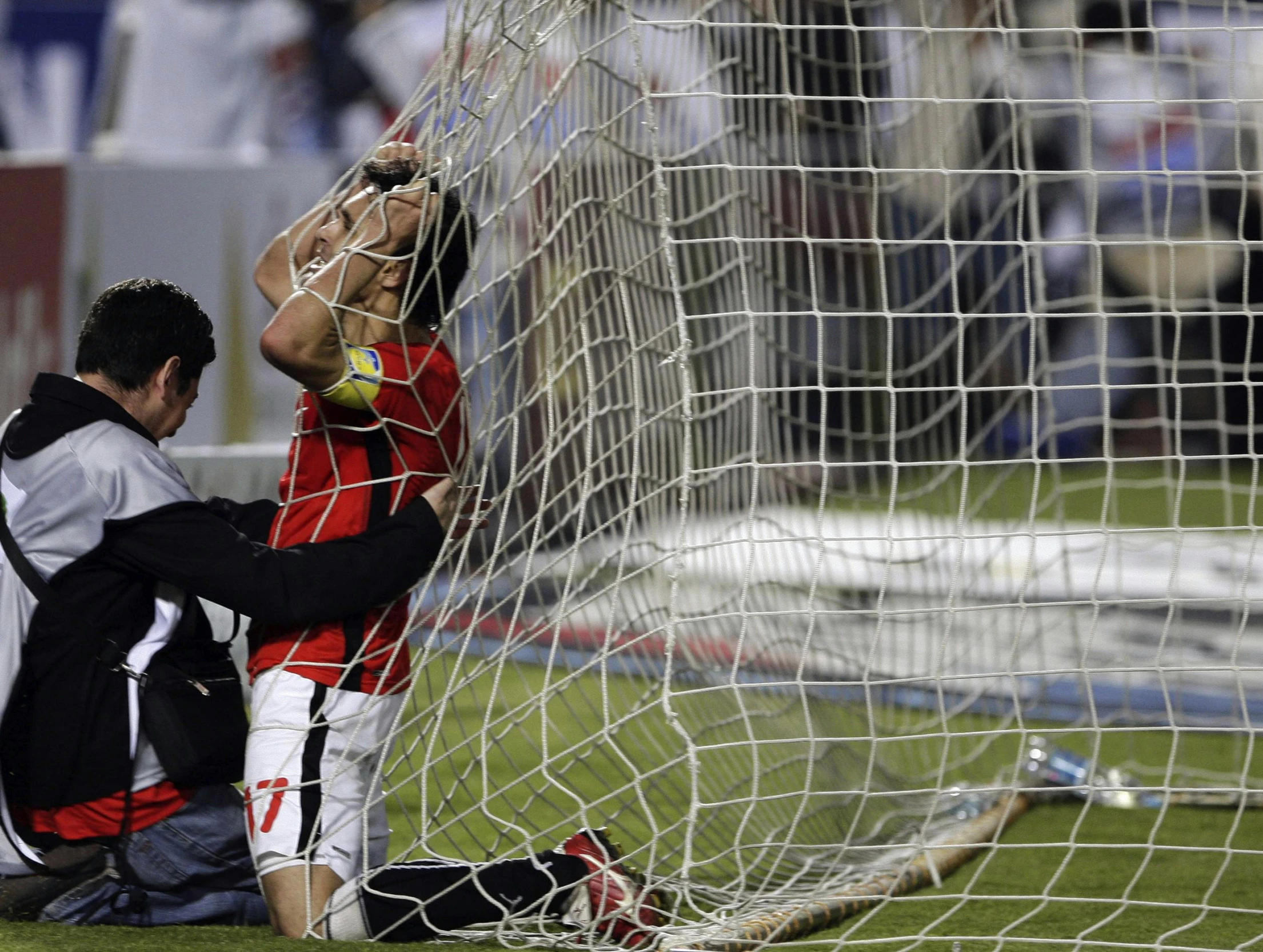 a soccer player putting on his cap by the net